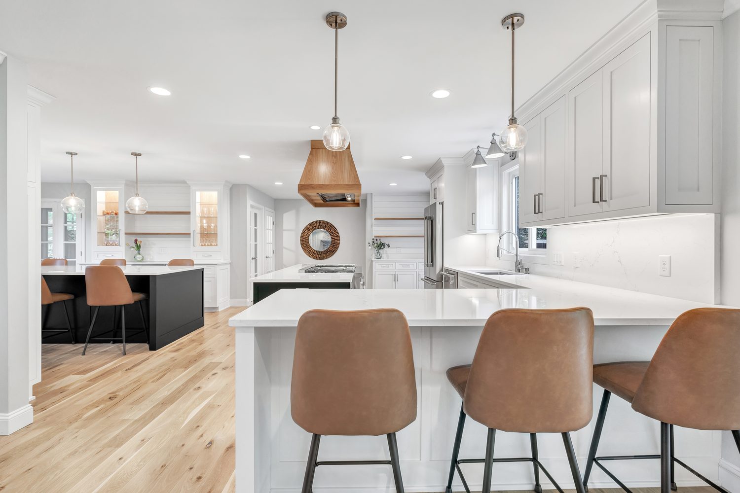 Bright white kitchen with island and leather stools in a classic remodel