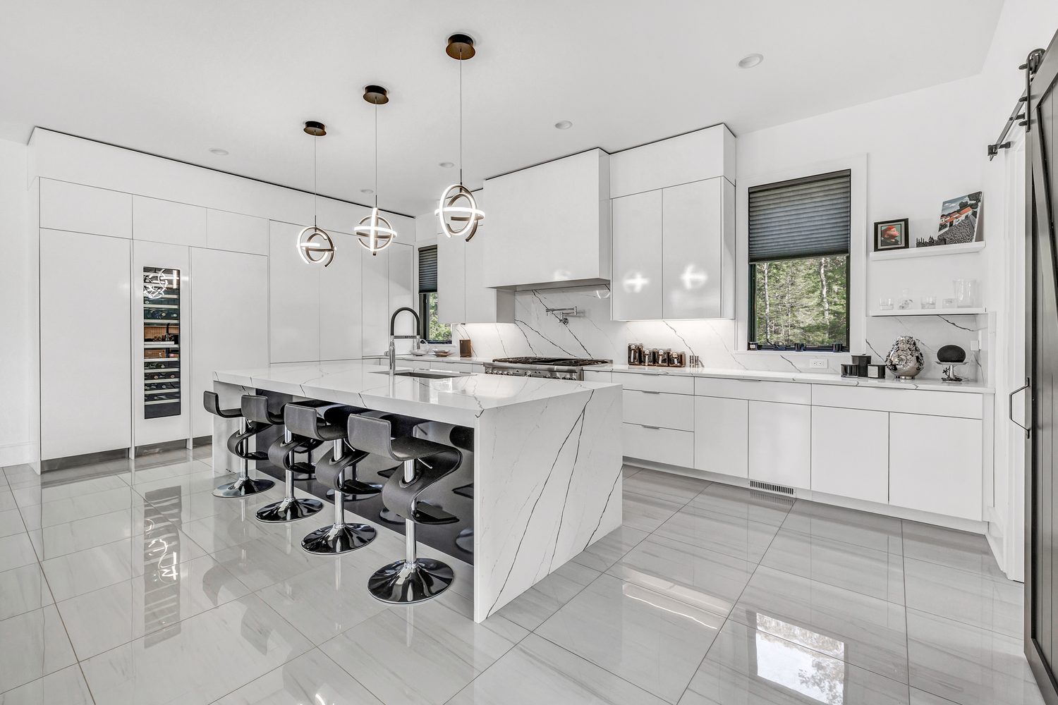 Minimalist all-white kitchen with hardwareless cabinetry and an island with stools