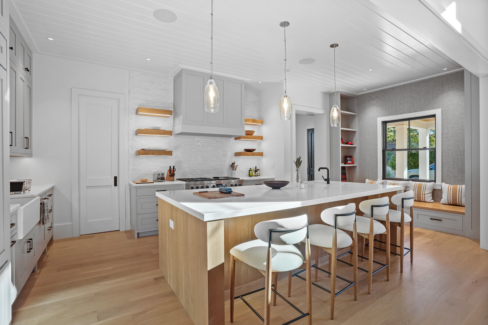 White oak kitchen with a waterfall island and floating shelves