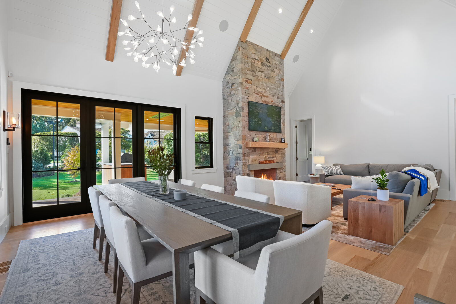 Great room with a stone fireplace and vaulted, beamed ceiling
